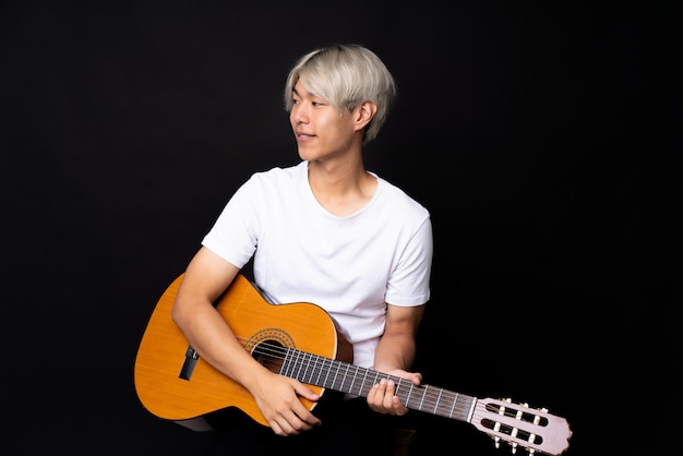 Jeune homme asiatique avec une guitare sur le côté noir