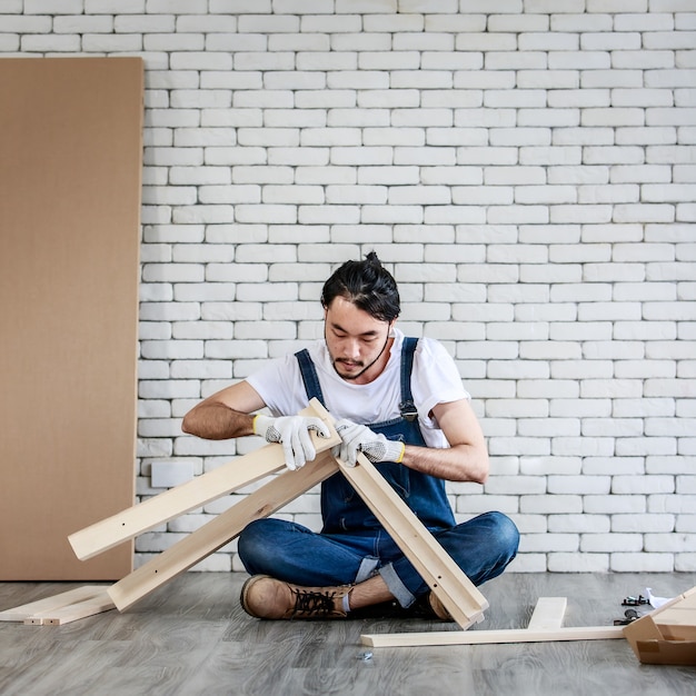 Jeune homme asiatique hipster travaillant comme bricoleur, assemblant une table en bois avec des équipements, concept de bricolage à domicile et libre-service à la maison.