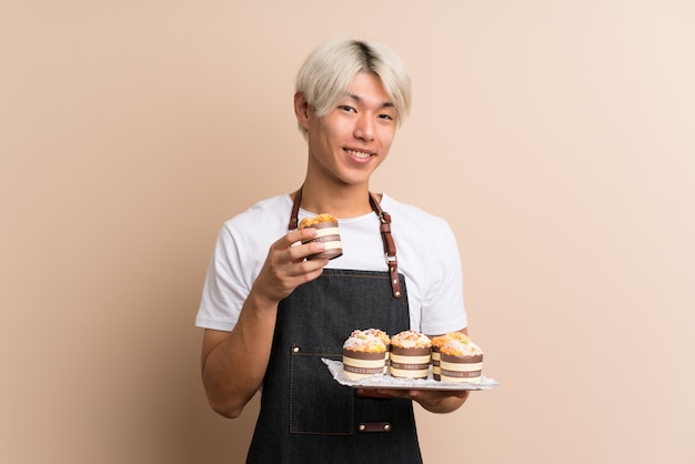 Jeune homme asiatique sur holding isolé mini gâteaux