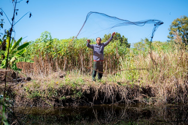 Jeune homme asiatique Ils pêchent en jetant leurs filets dans de petits étangs en plein air dans des jardins ou des fermes construites en Thaïlande à la campagne