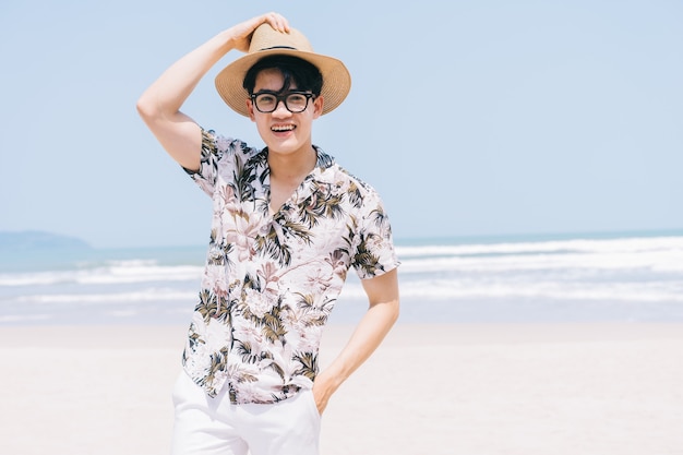 Jeune homme asiatique marchant sur la plage