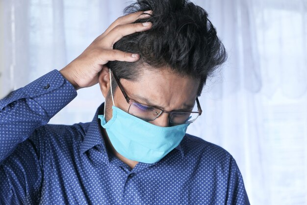 Un jeune homme asiatique avec un masque de protection au visage se sentir triste