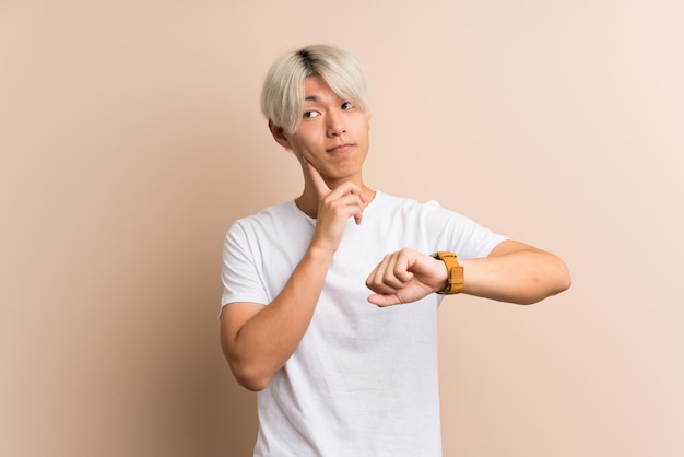 Jeune homme asiatique avec une montre au poignet et une idée