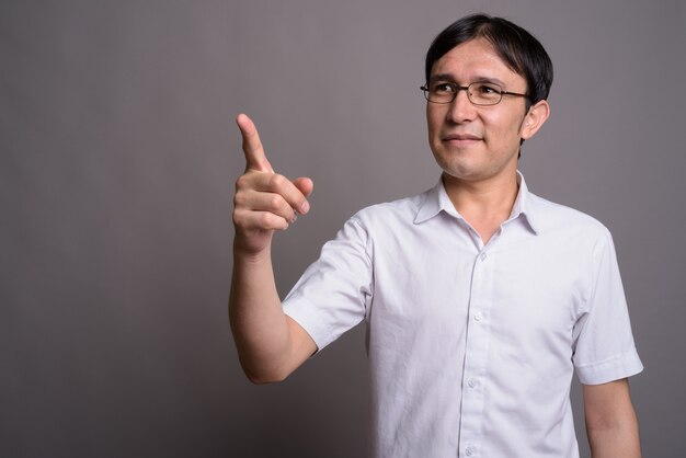 Jeune homme asiatique nerd portant des lunettes contre le mur gris