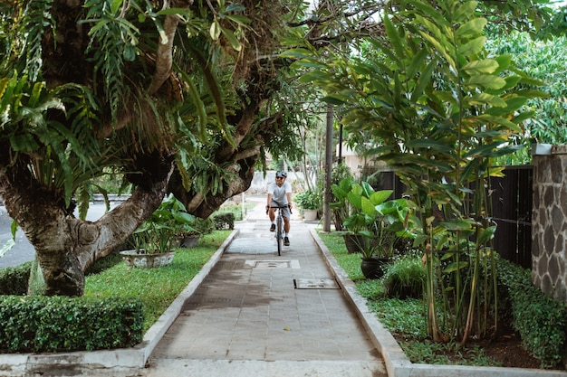 Jeune homme asiatique portant des casques de vélo lors de la conduite à vélo