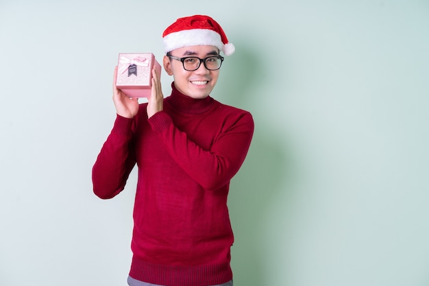 Jeune homme asiatique portant un chapeau de Noël sur fond vert