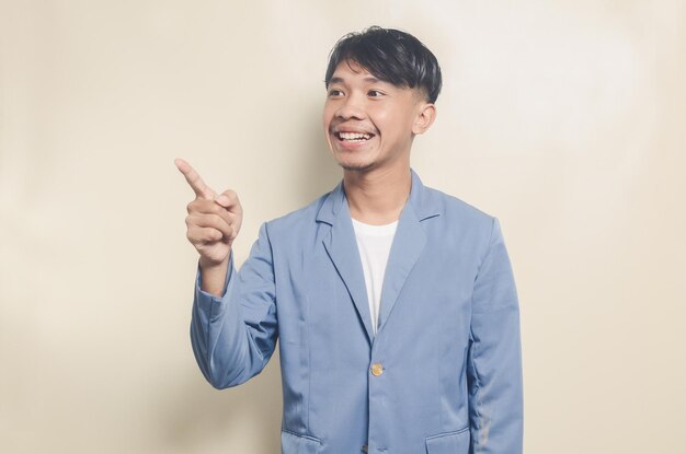 Jeune homme asiatique portant un costume d'université avec une expression de salutation sur fond isolé