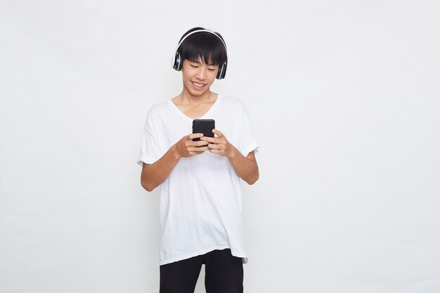 Jeune homme asiatique portant des écouteurs à partir d'un smartphone sur blanc