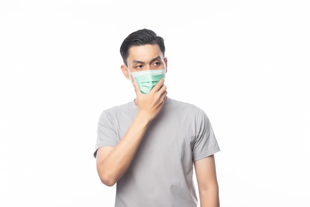 Jeune homme asiatique portant un masque hygiénique et pensant pour prévenir l'infection, 2019-nCoV ou coronavirus. Maladies respiratoires aéroportées telles que les combats du PM 2,5 et la grippe isolée