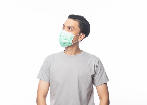 Jeune homme asiatique portant un masque hygiénique et regardant vers le fond pour prévenir l'infection, 2019-nCoV ou coronavirus. Maladies respiratoires aéroportées telles que les combats de pm 2,5 et la grippe isolé sur fond blanc