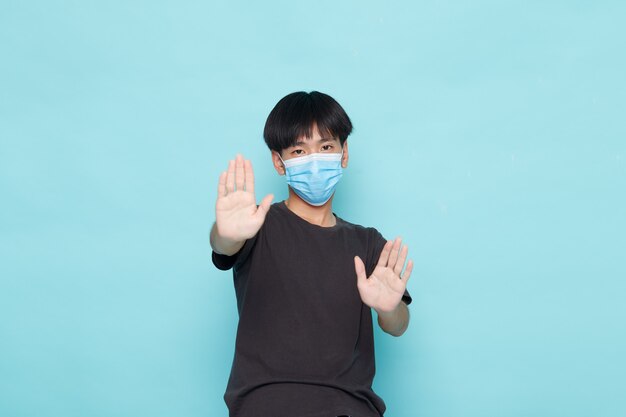 Jeune homme asiatique portant un masque médical jetable et gardant la distance sociale