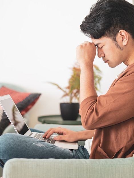 Jeune homme asiatique portant des vêtements décontractés et ayant un mal de tête