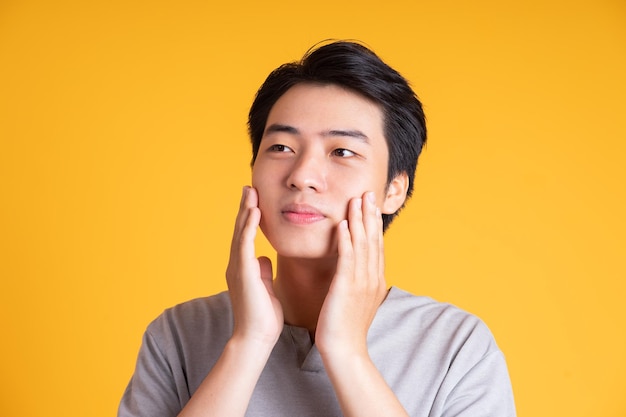 Jeune homme asiatique posant sur un fond jaune