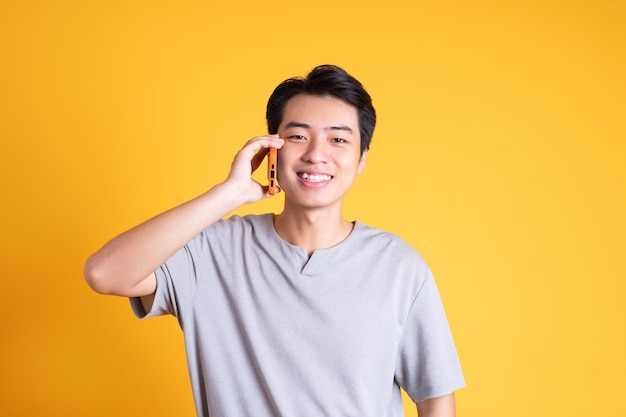 Jeune homme asiatique posant sur un fond jaune