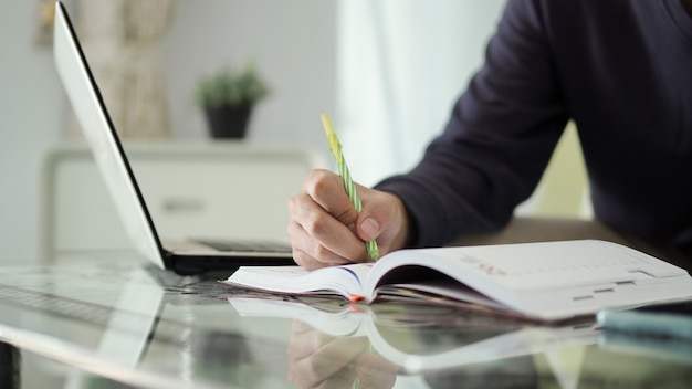 Jeune homme asiatique prenant des notes sur son travail à la maison