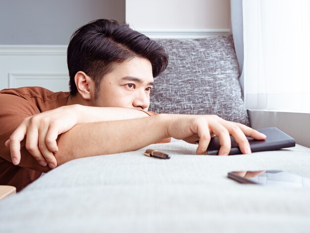 Jeune homme asiatique prenant une pause après avoir lu un livre à la maison