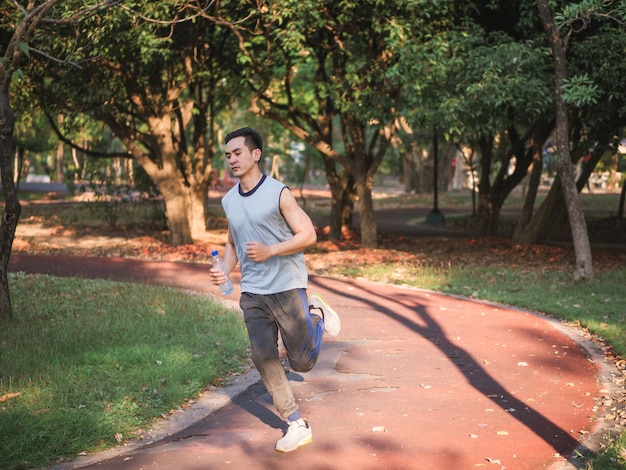 Jeune homme asiatique qui court dans le parc, concept de mode de vie sain.