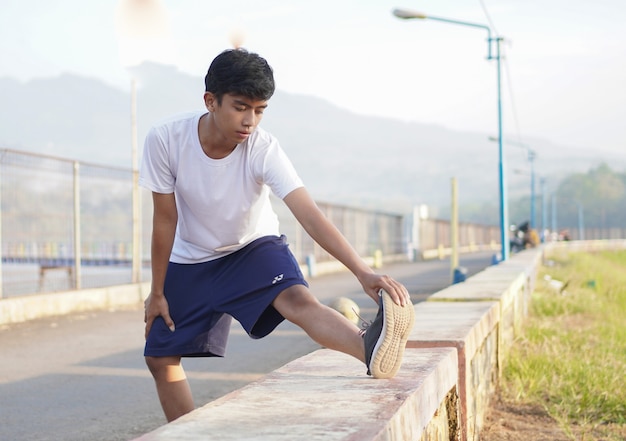 Jeune homme asiatique s'étirant avant de faire du jogging le matin