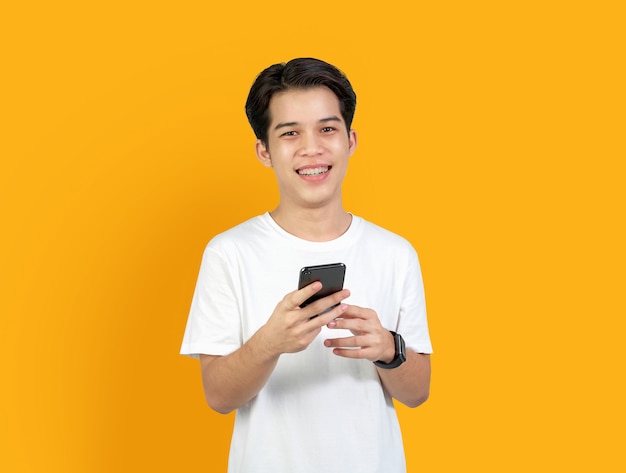 Jeune homme asiatique souriant avec téléphone intelligent sur orange