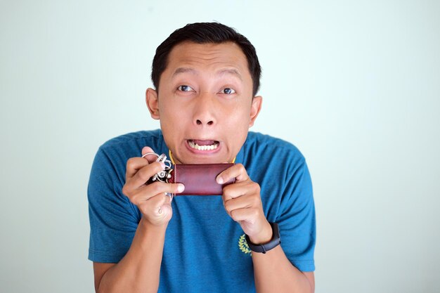 Photo jeune homme asiatique stupide tout en tenant une clé de voiture isolé sur fond blanc