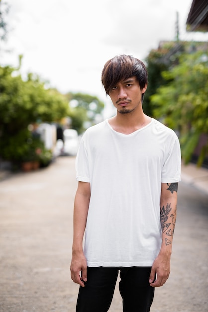 Jeune homme asiatique avec des tatouages à la main dans les rues à l'extérieur