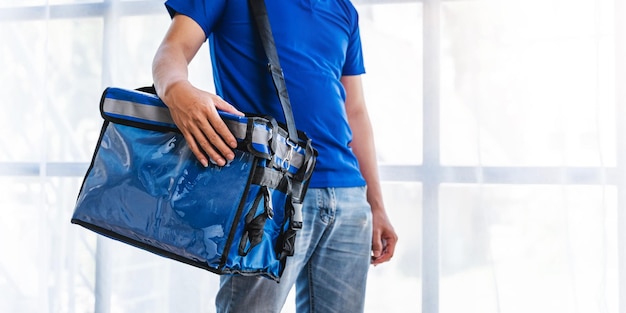 Jeune homme asiatique tenant un sac de nourriture et debout à l'intérieur du concept de boîte de livraison en studio