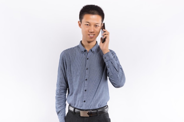 Jeune homme asiatique tenant un téléphone portable devant un fond blanc