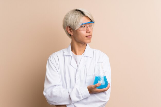 Jeune homme asiatique avec un tube à essai scientifique et à la recherche latérale