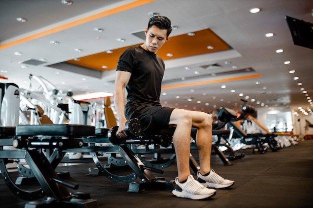 Jeune homme asiatique utilisant des exercices d'haltères au gymnase pour une bonne santé dans la forme physique Concept d'exercice de style de vie et de sport