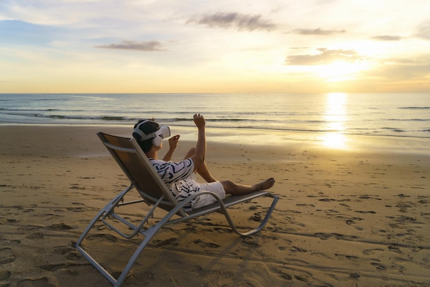 Jeune homme asiatique utilisant des lunettes de réalité virtuelle pour une réunion d'affaires sur la plage tropicale