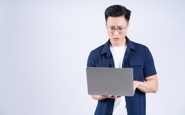 Jeune homme asiatique utilisant un ordinateur portable sur fond blanc