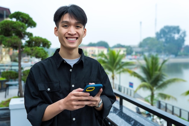 Jeune homme asiatique utilisant le téléphone au café
