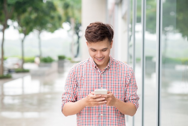 Jeune homme asiatique utilisant un téléphone intelligent en plein air