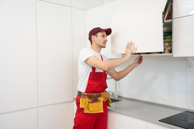 Jeune homme assemblant des meubles de cuisine.