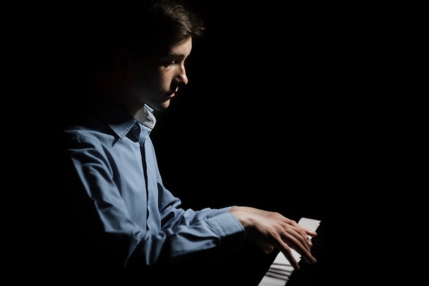 Jeune homme assis au piano.