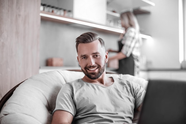 Jeune homme assis sur une chaise dans sa cuisine