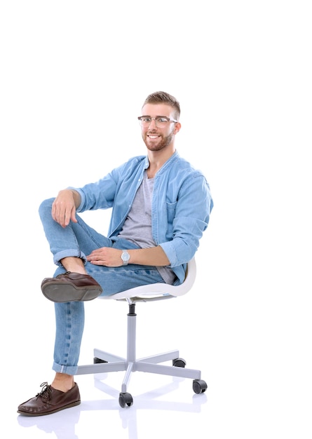 Jeune homme assis sur la chaise isolé sur fond blanc