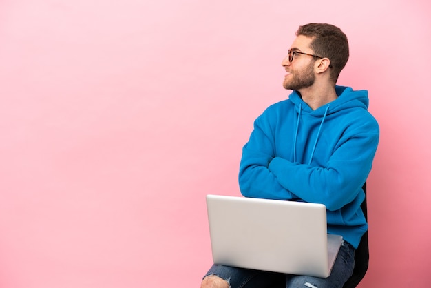 Jeune homme assis sur une chaise avec ordinateur portable en position latérale