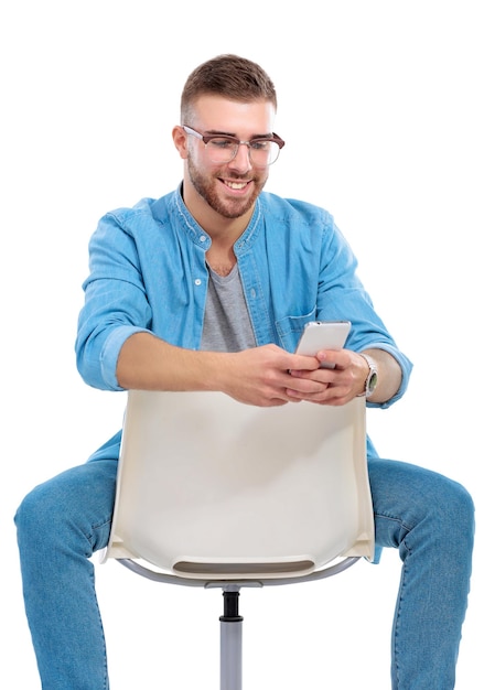 Jeune homme assis sur une chaise et utilisant un téléphone portable