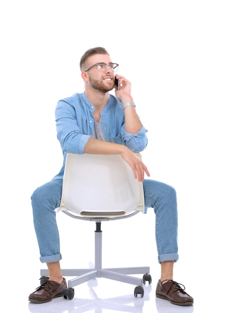 Jeune homme assis sur une chaise et utilisant un téléphone portable