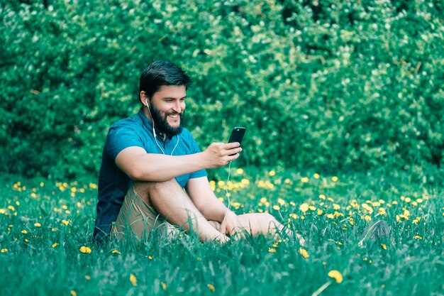 Jeune homme assis dans le parc et message texte