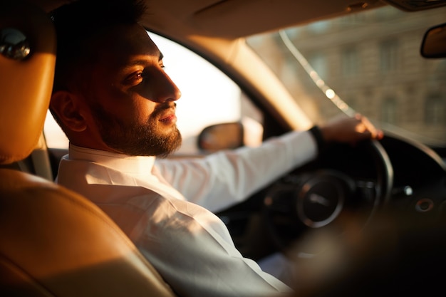 Jeune homme assis dans la voiture et penser à quelque chose pendant la conduite