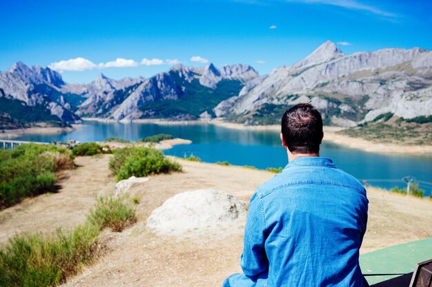 Photo jeune homme assis dos aux montagnes de riano dans les picos de europa