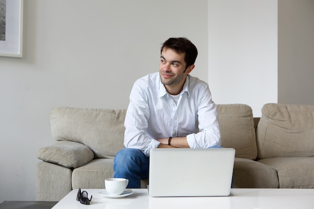 Jeune homme assis à la maison avec un ordinateur portable