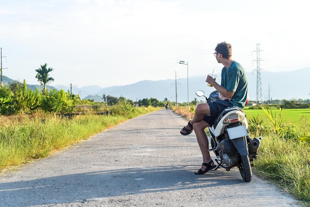 Jeune homme assis une moto parmi les rizières au Vietnam