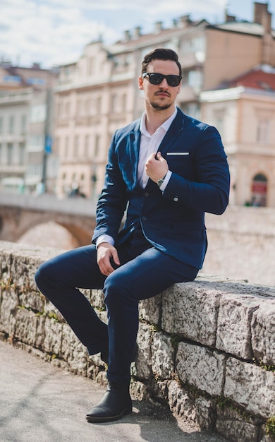 Un jeune homme assis sur une pierre en ville.
