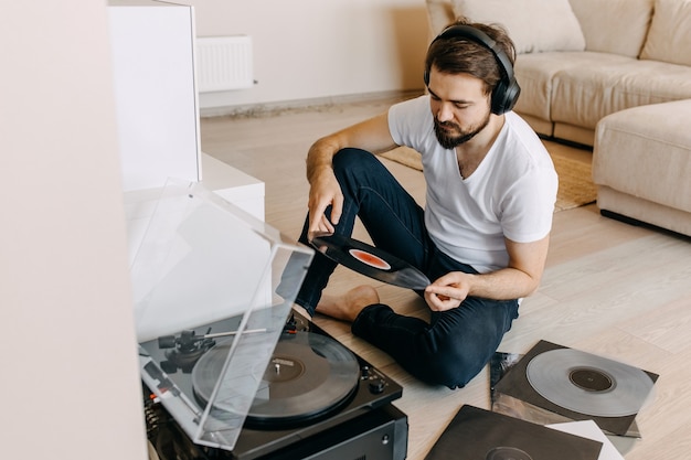 Jeune homme assis sur le sol, écoutant de la musique sur un lecteur de vinyle