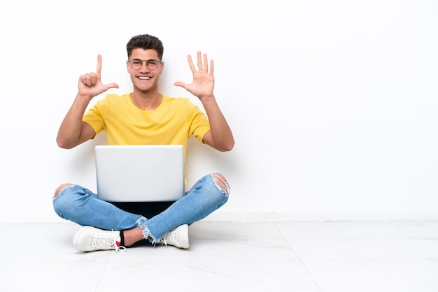 Jeune homme assis sur le sol isolé sur fond blanc comptant sept avec les doigts