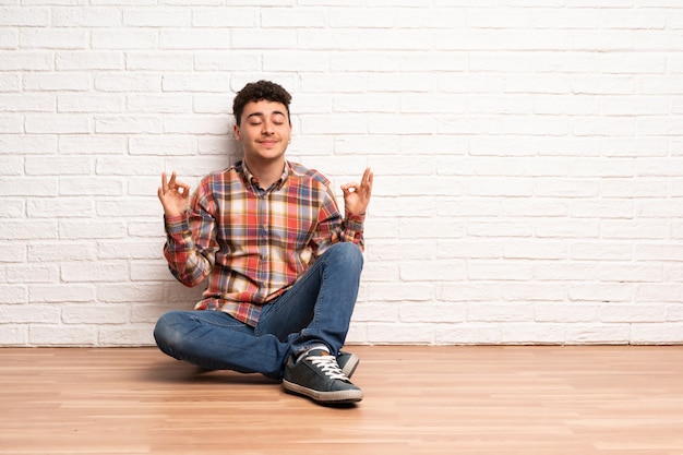 Jeune homme assis sur le sol en pose zen