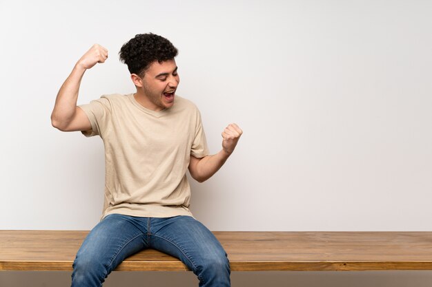 Jeune homme assis sur une table célébrant une victoire